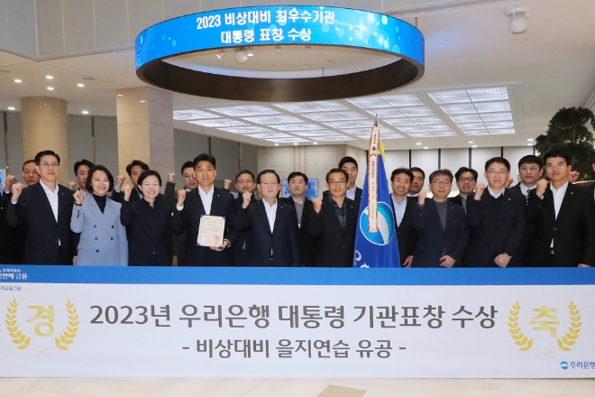 우리은행은 2023년 비상대비 을지연습을 실시한 전국 4000여 행정·공공기관·중점관리업체 중 우수기관으로 선정되어 대통령 표창을 수상했다고 28일 밝혔다. 사진은 우리은행이 2023년 비상대비 을지연습 유공으로 대통령 기관표창을 수상해 조병규 은행장과 임직원들이 우리은행 본점에서 기념촬영을 하고 있는 모습. (사진 = 우리은행 제공)