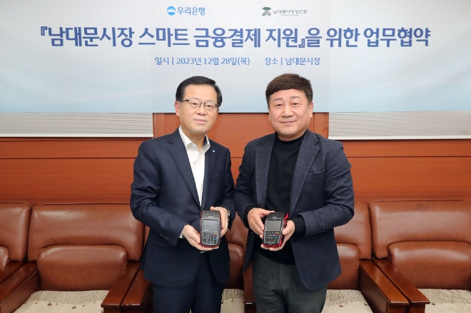 우리은행은 지난 28일 남대문시장 상인회와 ‘상생경영 및 동반성장을 위한 협약’을 체결하고 스마트 결제기기 지원을 통해 남대문시장 스마트 결제 인프라 구축을 지원하기로 했다고 29일 밝혔다. 사진은 (왼쪽부터)조병규 우리은행장과 문남엽 상인회 회장이 기념촬영을 하고 있는 모습. (사진 = 우리은행 제공)