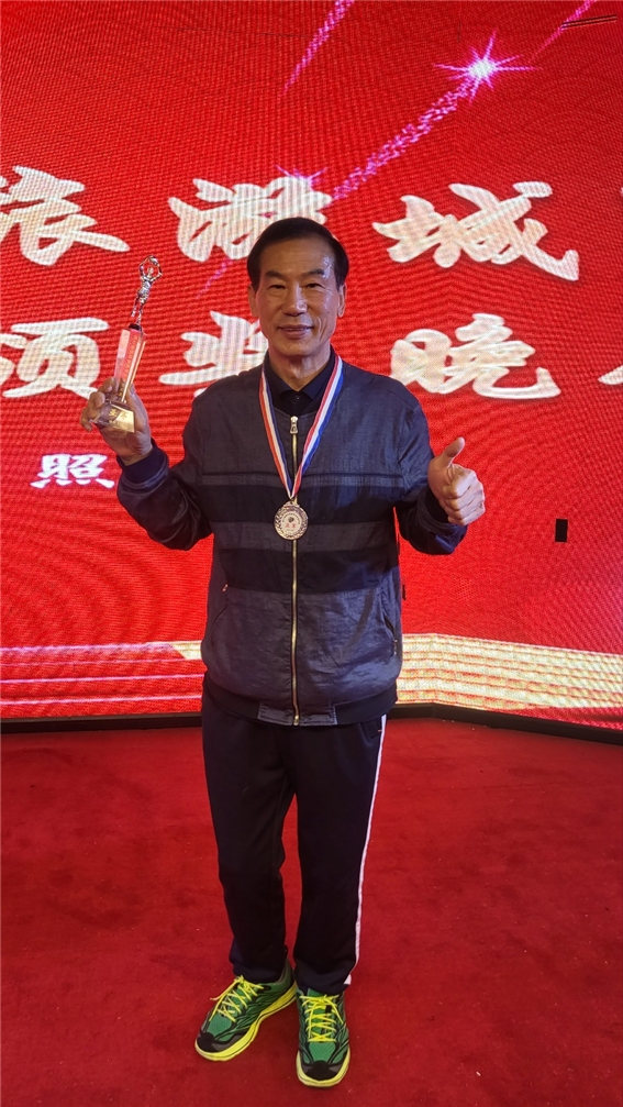 입상 목걸이와 트로피를 들고 포즈를 취한 박정길씨.