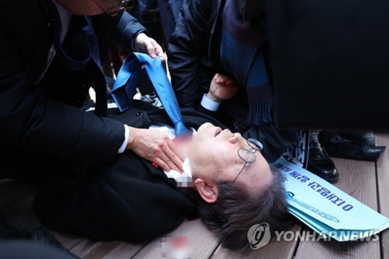 더불어민주당 이재명 대표가 2일 부산 가덕도 신공항 부지를 둘러본 후 기자들과 문답을 진행하던 중 왼쪽 목 부위에 습격을 당해 피를 흘린 채 쓰러져 있다.(사진=연합)