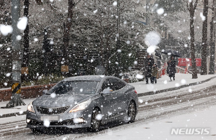 지난달 30일 서울 중구 명동 거리에서 시민들이 내리는 눈을 맞으며 발걸음을 재촉하고 있다.