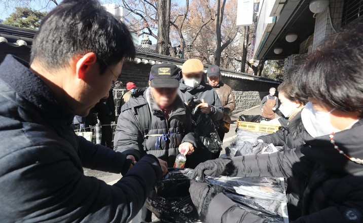 강력한 한파를 보인 날 서울 종로구 탑골공원 인근 무료급식소에서 관계자들이 어르신들에게 방한용품을 나누어주고 있다.