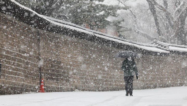 서울지역에 대설주의보가 내려진 지난달 30일 서울 종로구 세종대로 일대에서 한 시민이 우산을 쓰고 지나가고 있다.