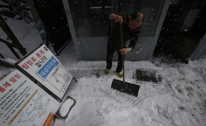대설주의보가 발효 중인 지난 14일 오후 강원 인제군 설악산 한계령 휴게소에 눈이 펑펑 내리자 휴게소 관계자가 눈을 치우고 있다.