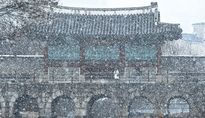  지난 15일 경기도 수원시 팔달구 화홍문에서 시민들이 눈을 맞으며 걷고 있는 모습.