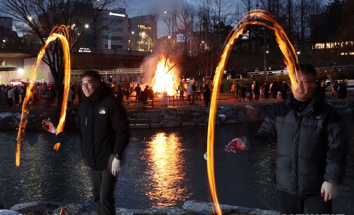 정월대보름을 하루 앞둔 지난 23일 서울 서초구 양재천에서 서초구 주최 정월대보름 축제가 열려 참여 구민들이 쥐불놀이를 하고 있다.
