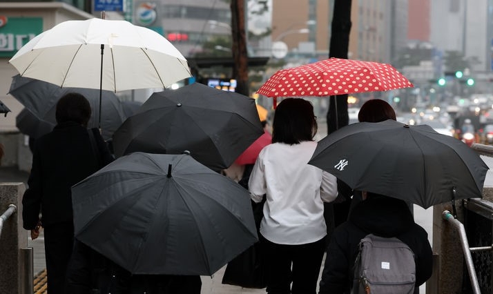 서울지역에 비가 내린 19일 서울 충무로역 인근에서 우산을 쓴 직장인들이 출근길 걸음을 재촉하고 있다.