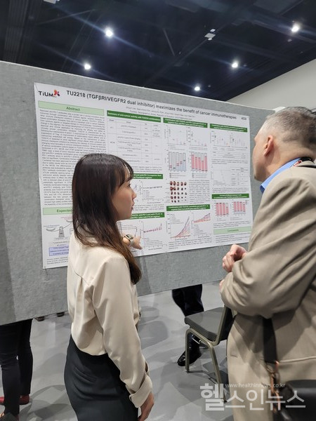 티움바이오연구원이AACR현장에서참석자를대상으로포스터에있는TU2218의실험결과를설명하고있다.