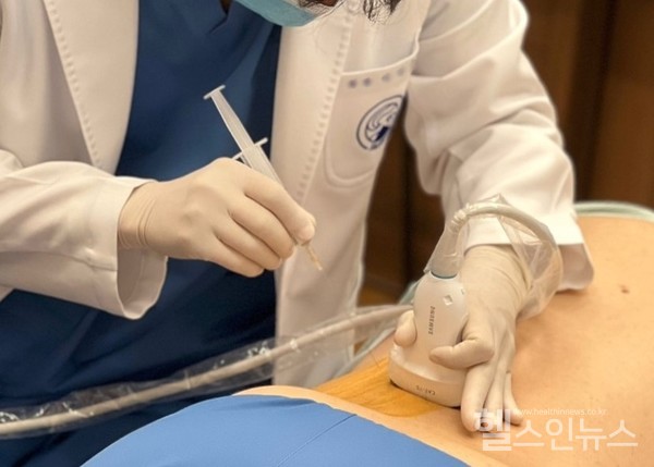 한의사가한방치료과정에서초음파진단기기를사용하고있다.