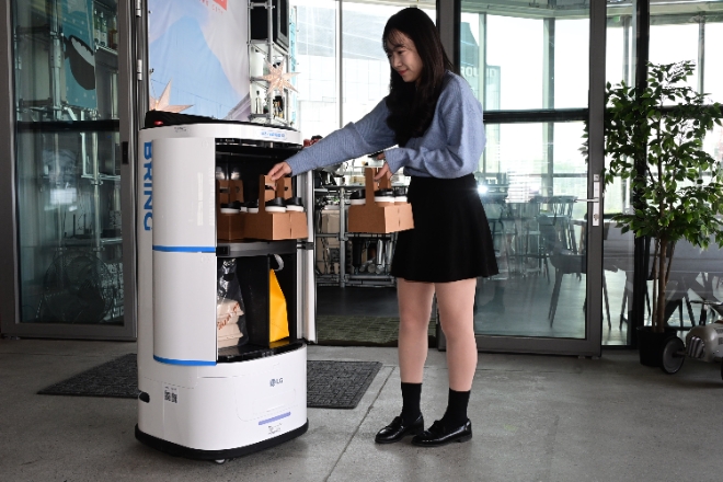 LG 클로이 서브봇(양문형)은 4칸의 서랍에 보통 크기(약 350㎖)의 커피를 최대 32잔까지 탑재할 수 있다. 공간 내부에는 위생을 고려해 항균 처리된 소재 및 탈취용 환기팬이 적용됐다. 사진은 LG전자 모델이 클로이 로봇의 서랍에 배송 물품을 적재하는 모습.