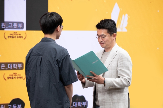 우아한형제들이 ‘2024 우아한 사장님 자녀 장학증서 수여식’을 개최하고 외식업주 고등학생, 대학생 자녀 330명에게 20억원 규모의 장학금을 전달했다. 우아한형제들 이국환 대표(오른쪽)가 외식업주 자녀에게 장학증서를 수여하고 있다.