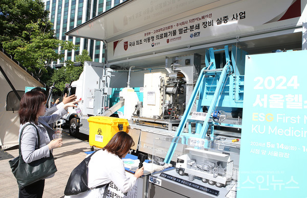 시민들이고려대의료원부스옆에설치된이동형의료폐기물멸균분쇄장비를구경하고있다