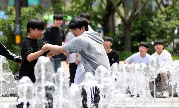 낮 기온이 최고 28도까지 오르며 초여름 날씨를 보인 17일 서울 종로구 광화문 광장을 찾은 학생들이 분수대에서 물놀이를 하고 있다.