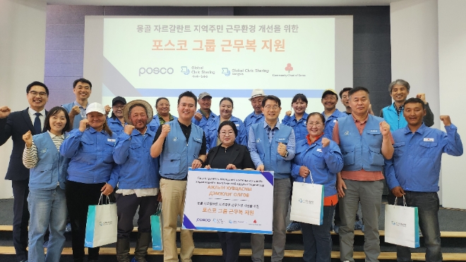 포스코 노사 관계자들이 몽골 주민들에게 구형 근무복을 전달하고 기념사진을 찍고 있다. / 사진=포스코 제공