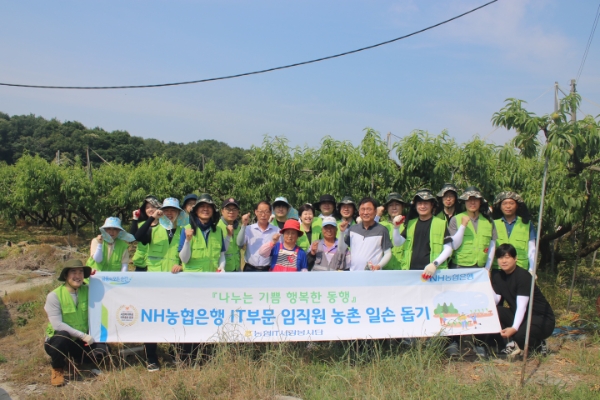 경기도 여주시 복숭아 농가에서 황재현 IT부문 부행장(플랜카드 잡고있는 사람 제외, 앞열 우측에서 네 번째) 및 직원들이 일손 돕기 행사후 기념사진을 촬영하고 있다. / 사진=NH농협은행 제공