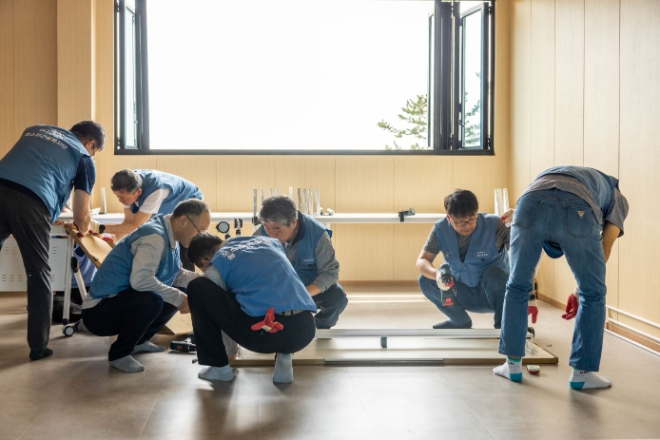 포스코이앤씨 직원들이 광양 소재 특수어린이집의 옥상 데크를 수리하고 있다. / 사진=포스코1%나눔재단 제공