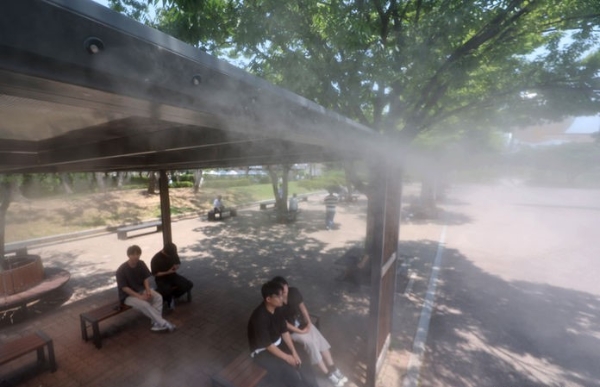 서울 지역의 낮 최고기온이 31도까지 오른 18일 서울 영등포구 여의도공원에서 시민들이 쿨링포그 아래서 더위를 피하고 있다.