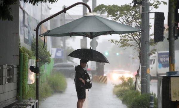 지난 20일 오후 제주 서귀포시 서홍동 인근 횡단보도에서 우산을 쓴 한 시민이 그늘막 아래서 보행신호를 기다리고 있다.
