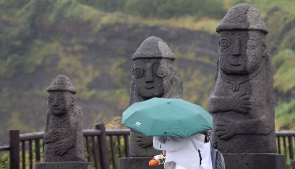 올해 첫 장맛비가 내린 지난 20일 오전 제주 서귀포시 대정읍 송악산 둘레길에서 우산을 쓴 관광객이 걸어가고 있다.