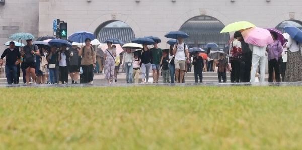 서울 등 중부지방에 비가 내리는 지난 22일 서울 종로구 광화문광장에서 시민들이 우산을 쓰고 이동하는 모습.