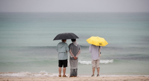 정체전선이 북상 중인 지난 27일 오후 제주시 구좌읍 월정해수욕장에서 우산을 쓴 관광객들이 장맛비가 내리는 여름 정취를 느끼는 모습.