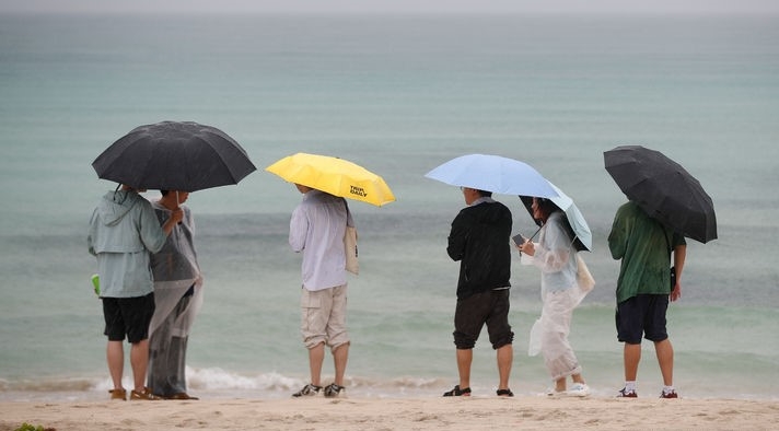정체전선이 북상 중인 지난 27일 오후 제주시 구좌읍 월정해수욕장에서 우산을 쓴 관광객들이 장맛비가 내리는 여름 정취를 느끼고 있는 모습.