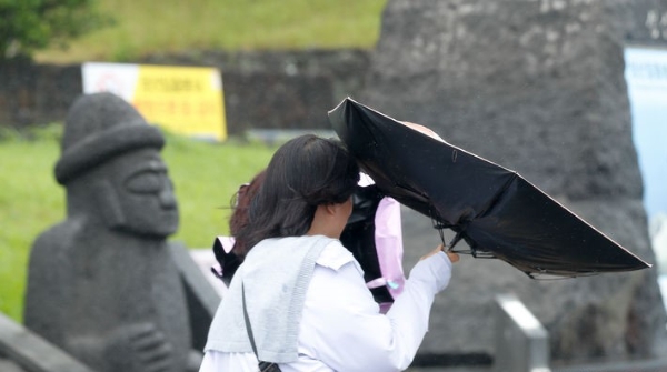 정체전선 영향으로 장맛비가 내린 30일 오후 제주 서귀포시 성산일출봉을 찾은 외국인 관광객들이 비바람을 피해 힘겹게 걸어가고 있다.