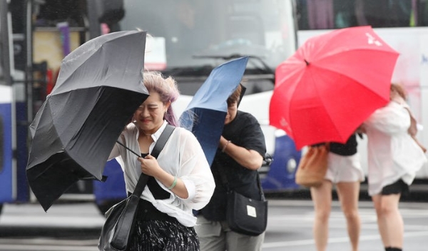 정체전선 영향으로 장맛비가 내린 지난달 30일 오후 제주 서귀포시 성산일출봉을 찾은 외국인 관광객들이 비바람을 피해 힘겹게 걸어가고 있다.