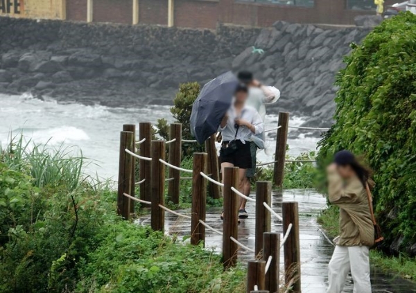 장맛비가 내리는 지닌달 30일 오후 제주시 애월읍 한담공원에서 우산을 쓴 관광객들이 산책하고 있다.