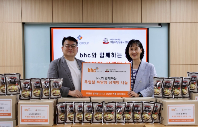 문상만 bhc 가맹사업본부장(왼쪽)이 성미선 서울시립 강동노인종합복지관 관장에게 삼계탕을 전달한 후 기념촬영을 하고 있다. / 사진=bhc그룹 제공