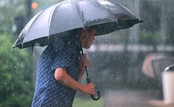 소나기가 쏟아진 8일 오후 광주 서구 운천저수지 주변에서 한 시민이 우산을 쓴 채 발걸음을 옮기고 있다.