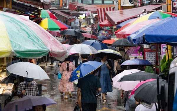 장맛비가 내린 8일 서울 동작구 남성사계시장에서 우산을 쓴 시민들이 발걸음을 옮기고 있다.