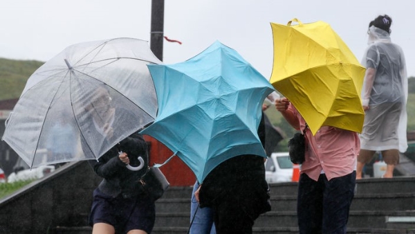 정체전선 영향으로 장맛비가 내린 지난 달 30일 오후 제주 서귀포시 성산일출봉을 찾은 외국인 관광객들이 비바람을 피해 힘겹게 걸어가고 있다.