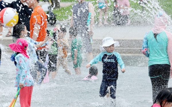 낮 최고기온이 33도까지 오르면서 무더운 날씨를 보인 13일 서울 영등포구 여의도 한강공원 물빛광장에서 어린이들이 물놀이를 하며 더위를 식히고 있다.