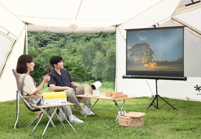 삼성전자 모델이 '스노우피크 에버랜드 캠프필드'의 캠핑장에서 포터블 스크린 '더 프리스타일 2세대'로 콘텐츠를 즐기고 있다.