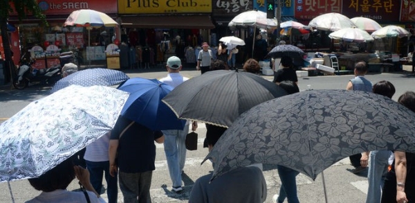 연일 무더위가 이어지고 있는 18일 전북 전주시 전주신중앙시장을 찾은 시민들이 양산으로 햇빛을 피하며 길을 지나고 있다.