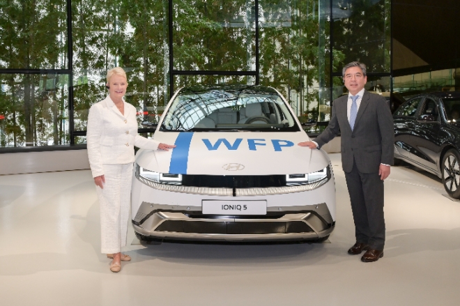 장재훈 현대차 사장(오른쪽)과 신디 매케인 WFP 사무총장이 WFP 로고로 랩핑한 아이오닉 5 옆에서 기념사진을 찍고 있다. / 사진=현대차 제공