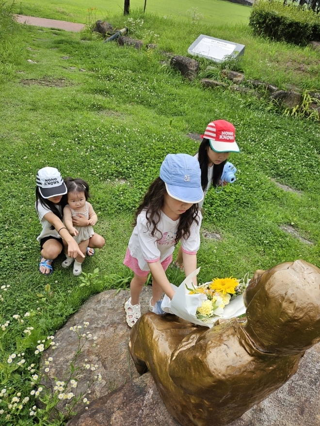 경기도가 지난달 오는 10일 위안부 피해자 기림의날 행사에 맞춰 진행한 '기억의 꽃배달' 행사에서 전남 구례에 사는 젖먹이 유아를 포함한 네자매가 소녀상에 꽃다발을 선사하고 있다.(사진=경기도)