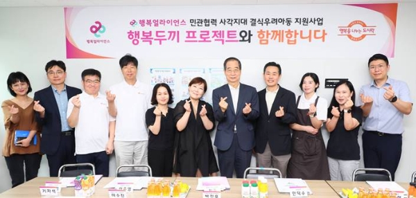 성북구 행복도시락센터에서 한덕수 국무총리(오른쪽에서 다섯번째)와 조민영 행복얼라이언스 본부장(오른쪽에서 네번째), 임은미 행복얼라이언스 실장(오른쪽에서 여섯번째), 최준 행복도시락사회적협동조합 사무국장(오른쪽에서 여덟번째), 송정아 성북구 아동청소년팀 팀장(오른쪽에서 두번째)을 비롯한 여러 관계자가 단체 사진을 촬영하고 있다. (사진 제공: 행복얼라이언스)