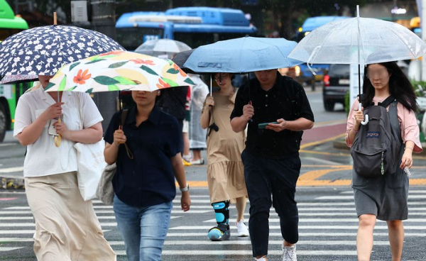 서울 시내에 소나기가 내리는14일 서울 종로구 세종대로에서 시민들이 비를 피해 퇴근하고 있다.
