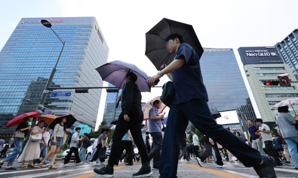 서울 시내에 소나기가 내리는14일 서울 종로구 세종대로에서 시민들이 비를 피해 퇴근하고 있다.