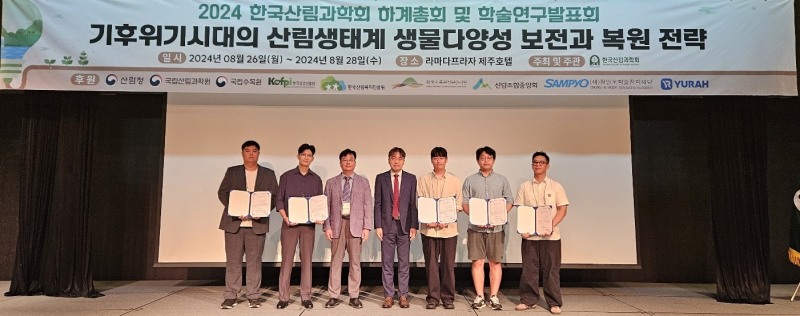 유용재 정인욱학술장학재단 사무국장(사진 가운데)과 이상현 한국산림과학회장(사진 왼쪽에서 세번째), 산림 Pioneer 육성 장학생 3기 5명이 지난 27일 라마다프라자 제주호텔에서 열린 장학증서 전달식에서 기념촬영을 하고 있다. (사진 제공=정인욱학술장학재단)