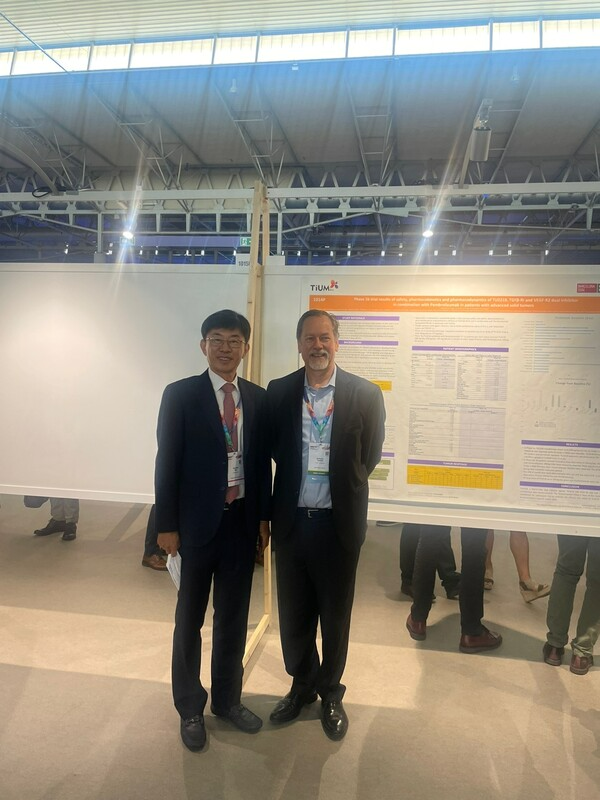티움바이오 김훈택 대표와 임상 1b상 책임자(Principal Investigator)인 Tolcher박사가 포스터 앞에서 포즈를 취하고 있다. (티움바이오 제공)