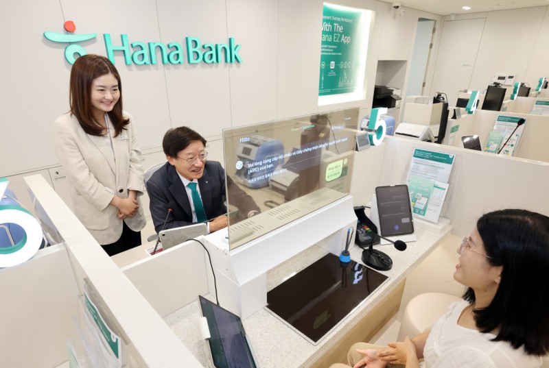 하나은행은 19일 경기도 평택시 평택동에 소재한 외국인 전용 특화점포 '평택외국인센터점'을 개점했다. 이승열 하나은행장(사진 가운데)이 실시간 다국어 통번역 시스템이 설치된 창구에 앉아 투명디스플레이를 통해 외국인 손님을 응대하고 있다.