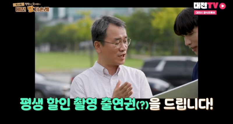 사진=대전 홍보담당관 이호영(좌)씨가 가수 김동찬(우)에게 '평생 할인 촬영 출연권'을 전달하고 있다. / 출처=대전TV 캡쳐