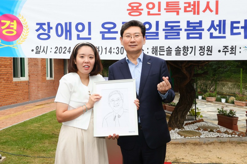 이상일 용인특례시장(오른쪽)에게 직접 그린 캐리커쳐를 선물한 발달장애인 화가 이미경 작가(왼쪽)
