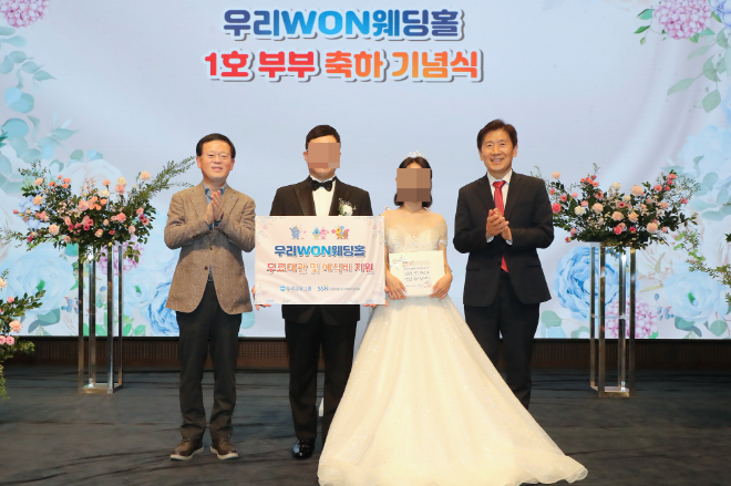 지난 13일 취약계층 신혼부부의 결혼식을 위해 우리금융 본사 사옥 웨딩홀을 무료로 대관해 주는 ‘우리 WON 웨딩홀’ 1호 부부가 탄생했다. (왼쪽부터) 조병규 우리은행장, ‘우리 WON 웨딩홀’ 1호 부부, 김현훈 서울특별시사회복지협의회장이 기념촬영을 하고 있다. ⓒ 우리금융