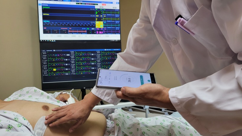 환자에게 부착한 체온 패치로 측정한 체온을 의료진이 단말기로 확인하고 있다.