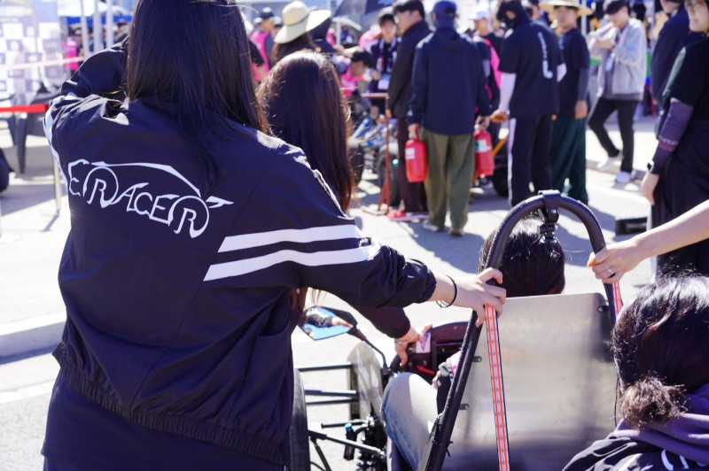 형지엘리트의 워크웨어 브랜드 ‘월비워크웨어’가 ‘2024 대학생 스마트 e-모빌리티 경진대회’에 출전한 이화여자대학교 자작차 동아리 ‘이레이서’에 단체복을 후원했다. 사진은 윌비워크웨어 점퍼를 입고 대회에서 출발을 준비하는 이레이서 팀원의 모습