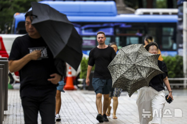 절기상 '처서'인 22일 서울 중구 세종대로에서 우산을 쓴 시민들이 비바람을 맞으며 이동하고 있다.